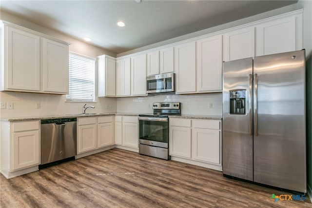 kitchen with white cabinetry, stainless steel appliances, tasteful backsplash, and dark hardwood / wood-style flooring