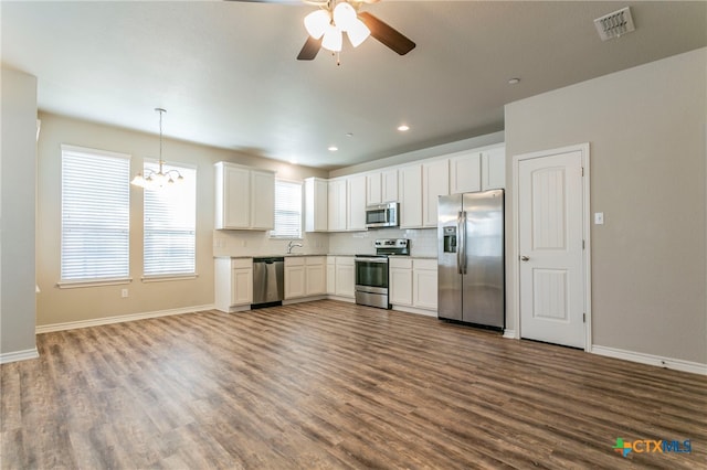 kitchen with white cabinetry, appliances with stainless steel finishes, hardwood / wood-style flooring, and pendant lighting