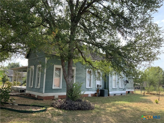 view of side of property with a lawn and cooling unit