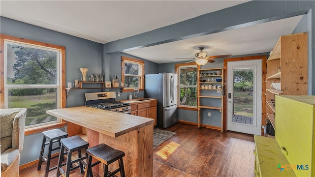 kitchen with kitchen peninsula, plenty of natural light, a breakfast bar, and appliances with stainless steel finishes