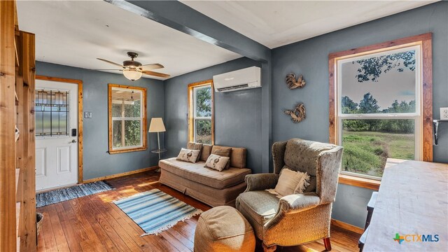 living area featuring dark wood-type flooring, a wall unit AC, and ceiling fan