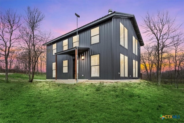 back house at dusk featuring a lawn