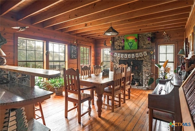 1218 Oakwood Loop, San Marcos, TX 78666 - dining space with a stone fireplace, wooden walls, hardwood / wood-style flooring, and healthy amount of natural light