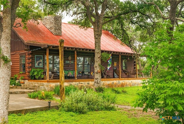 1218 Oakwood Loop, San Marcos, TX 78666 - rear view of house with log siding, a chimney, and a metal roof