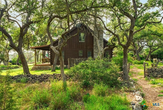 1218 Oakwood Loop, San Marcos, TX 78666 - view of side of home with log exterior, board and batten siding, and a chimney