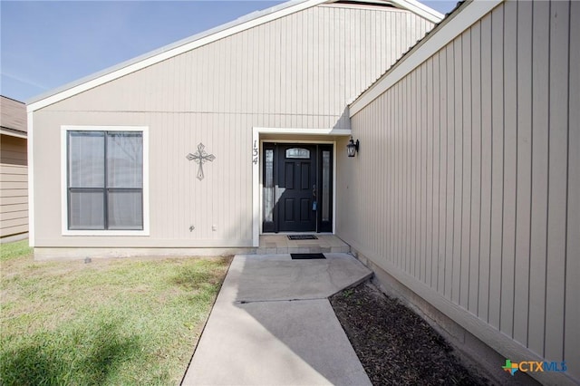 view of exterior entry featuring a lawn