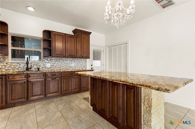 kitchen with tasteful backsplash, sink, hanging light fixtures, and a kitchen island