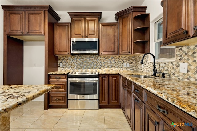 kitchen featuring light stone counters, appliances with stainless steel finishes, sink, and tasteful backsplash