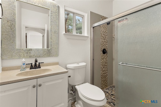 bathroom featuring vanity, toilet, and a shower with shower door