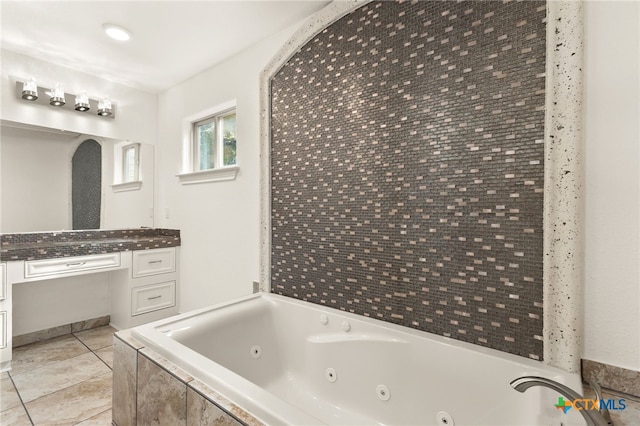 bathroom with tile patterned flooring, vanity, and tiled bath