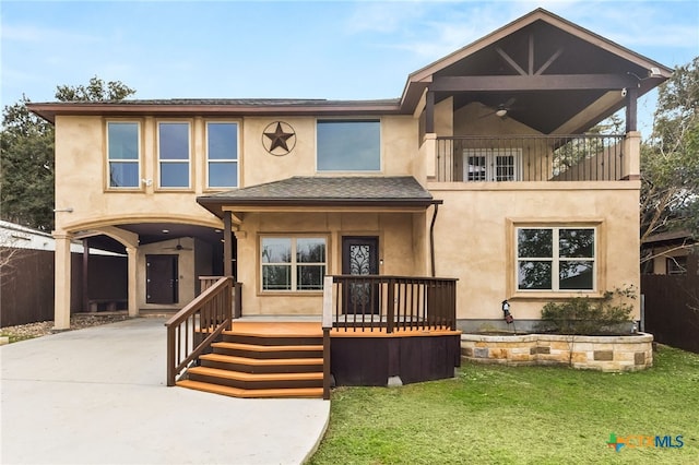 view of front of property with a balcony, ceiling fan, and a front lawn