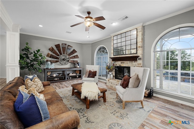 living area with ornamental molding, visible vents, ceiling fan, and wood finished floors