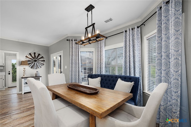 dining space with visible vents, plenty of natural light, crown molding, and light wood finished floors