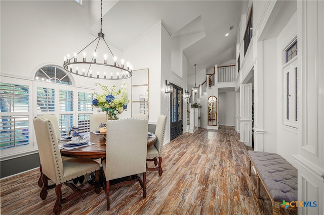 dining space with a chandelier, high vaulted ceiling, and wood finished floors