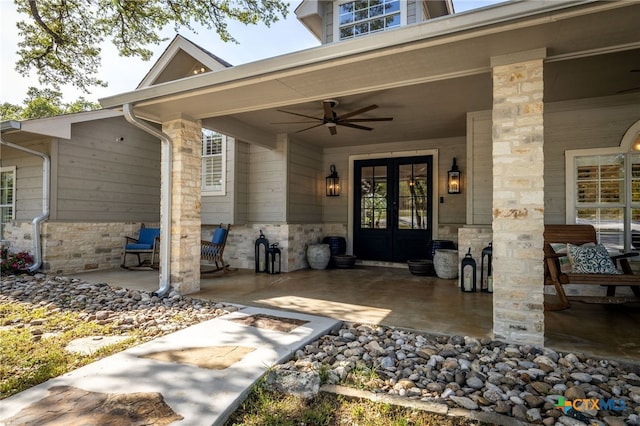 view of exterior entry featuring ceiling fan, french doors, and stone siding