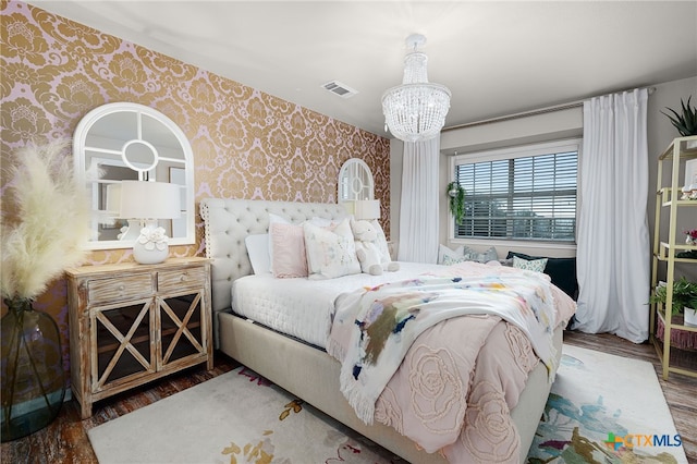 bedroom featuring visible vents, wallpapered walls, wood finished floors, and an inviting chandelier