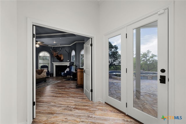 entryway with wood finished floors, ceiling fan, ornamental molding, and a fireplace