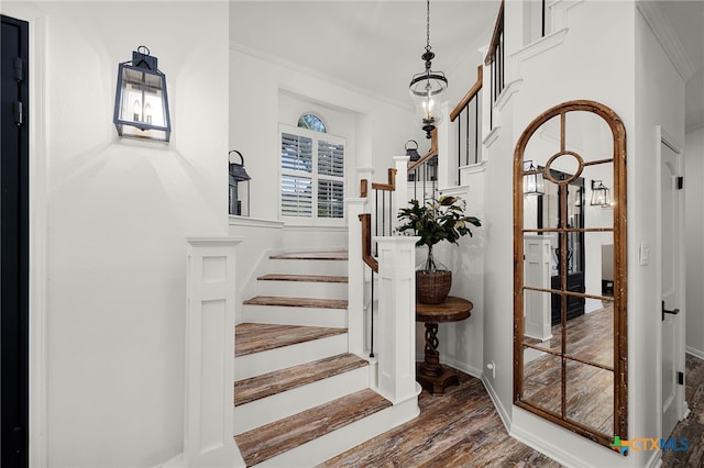 staircase with ornamental molding, wood finished floors, and baseboards