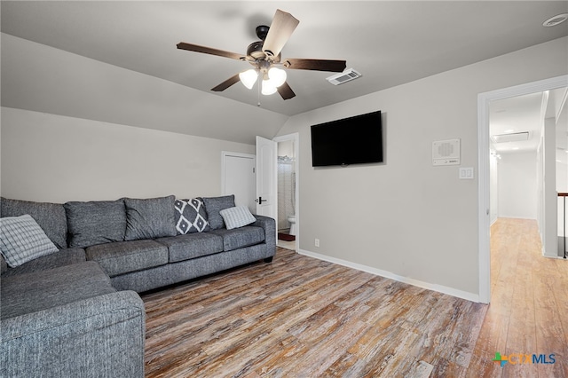 living area featuring light wood finished floors, ceiling fan, visible vents, baseboards, and lofted ceiling
