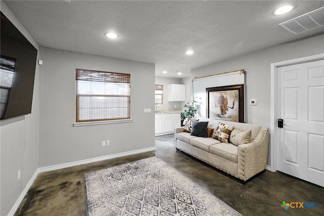 living area featuring concrete floors, visible vents, recessed lighting, and a textured ceiling