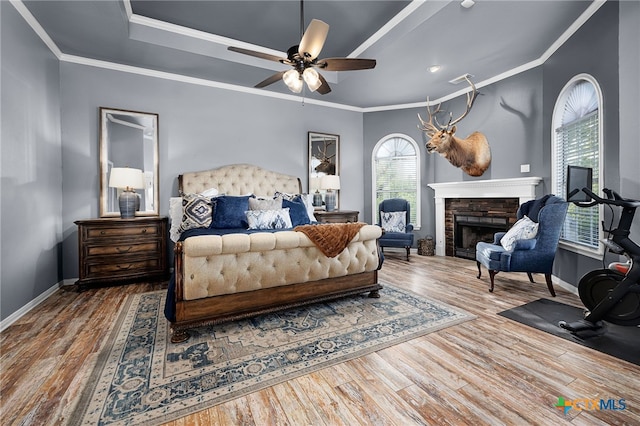 bedroom featuring a fireplace, wood finished floors, baseboards, and multiple windows