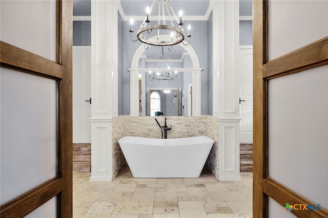 bathroom with a freestanding tub, ornamental molding, an inviting chandelier, and stone tile flooring