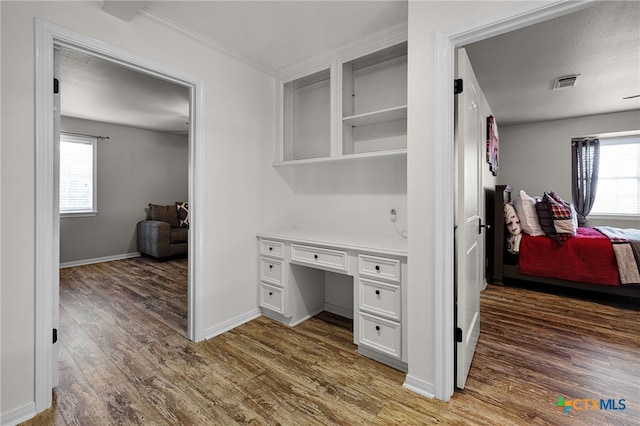 interior space with baseboards, visible vents, wood finished floors, and crown molding