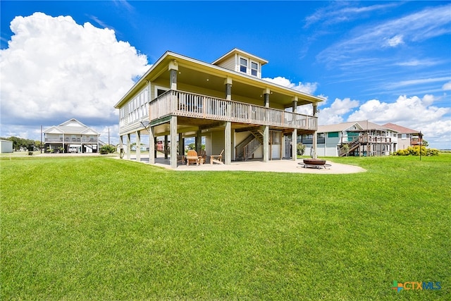 rear view of house with a fire pit, a deck, a yard, and a patio