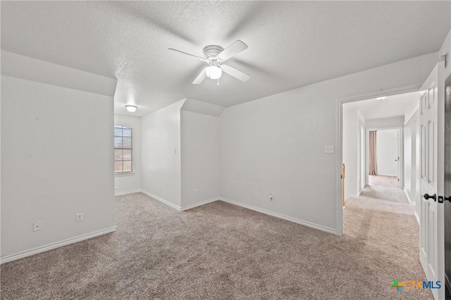 empty room featuring ceiling fan, light colored carpet, and a textured ceiling