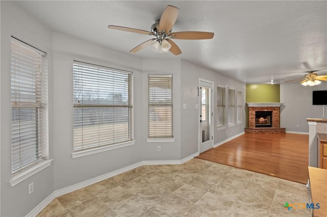 interior space with a brick fireplace and ceiling fan