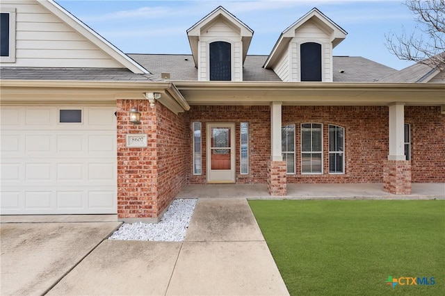 entrance to property with a garage, a yard, and covered porch