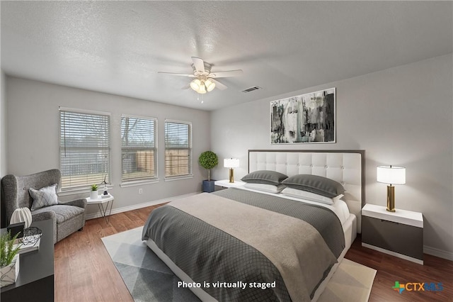 bedroom featuring ceiling fan, hardwood / wood-style flooring, and a textured ceiling