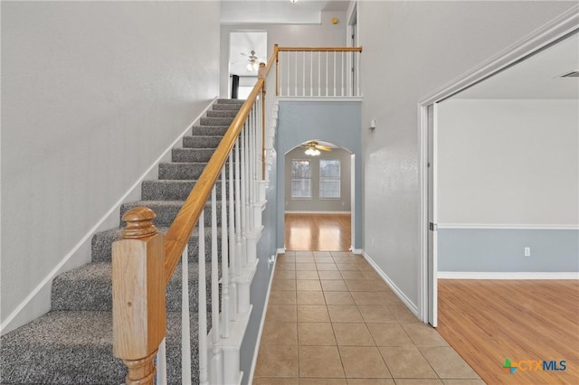 stairway featuring a towering ceiling, tile patterned floors, and ceiling fan