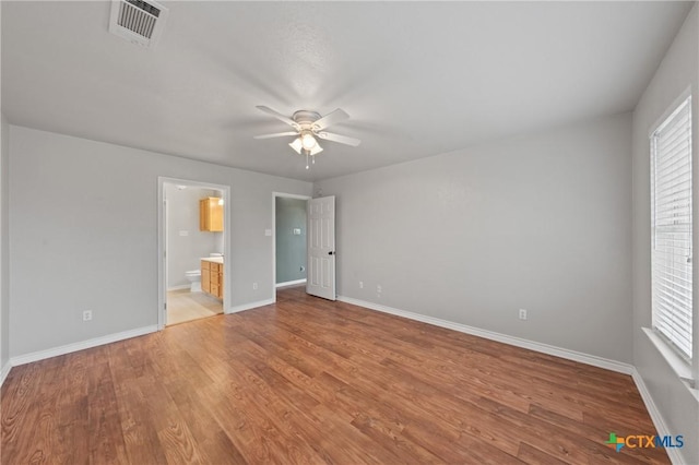 unfurnished bedroom with multiple windows, ceiling fan, connected bathroom, and light hardwood / wood-style floors