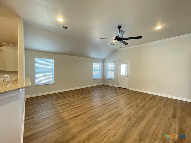 unfurnished living room featuring baseboards, visible vents, vaulted ceiling, and wood finished floors