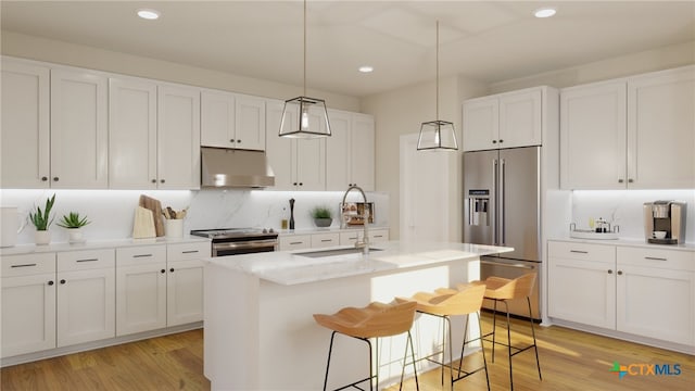 kitchen featuring light hardwood / wood-style floors, appliances with stainless steel finishes, a kitchen breakfast bar, a kitchen island with sink, and white cabinets