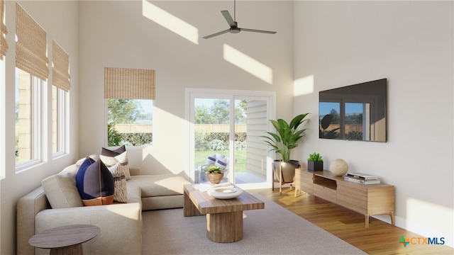 living room with hardwood / wood-style floors, ceiling fan, and a towering ceiling