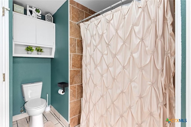 bathroom featuring toilet, curtained shower, and tile patterned flooring