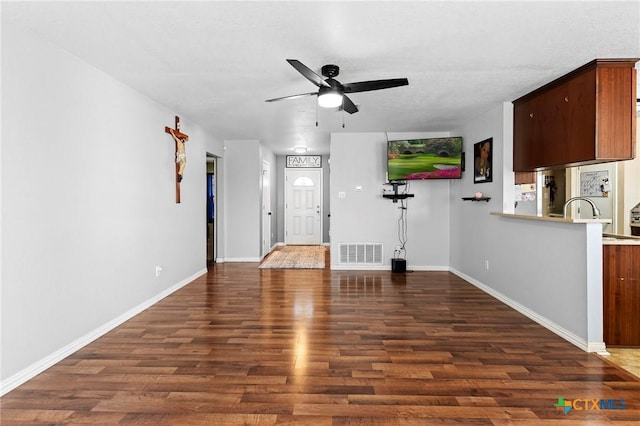 unfurnished living room featuring dark wood-type flooring and ceiling fan