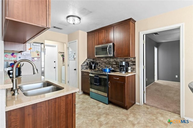 kitchen featuring sink, light colored carpet, stainless steel appliances, light stone countertops, and decorative backsplash