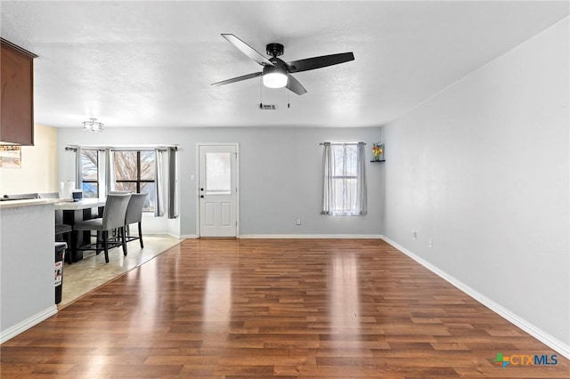 unfurnished living room with ceiling fan, wood-type flooring, and plenty of natural light