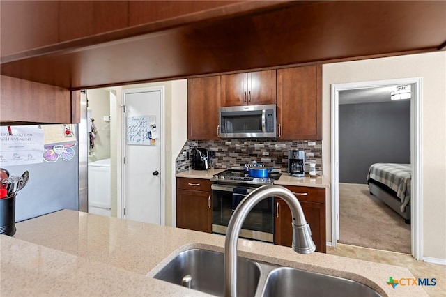 kitchen with light carpet, sink, decorative backsplash, and stainless steel appliances