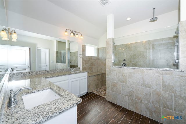 bathroom featuring vaulted ceiling, vanity, an inviting chandelier, and a tile shower