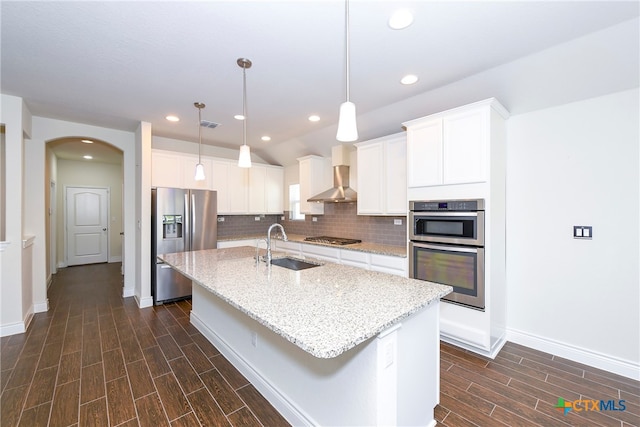 kitchen featuring white cabinets, stainless steel appliances, a center island with sink, and dark hardwood / wood-style flooring