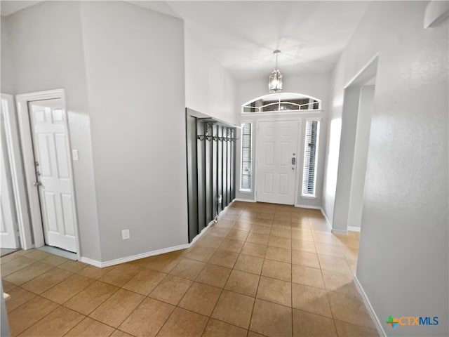 foyer with light tile patterned flooring, a high ceiling, and an inviting chandelier