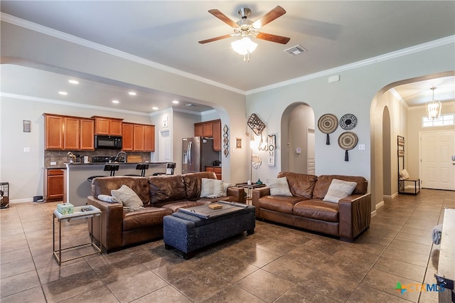 tiled living room with ceiling fan and crown molding