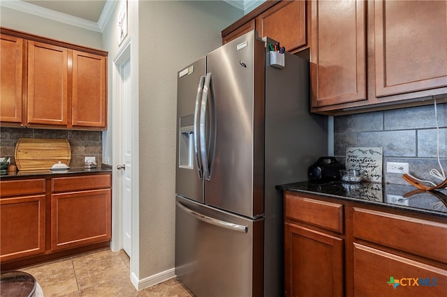 kitchen with ornamental molding, stainless steel fridge with ice dispenser, light tile patterned floors, decorative backsplash, and dark stone countertops