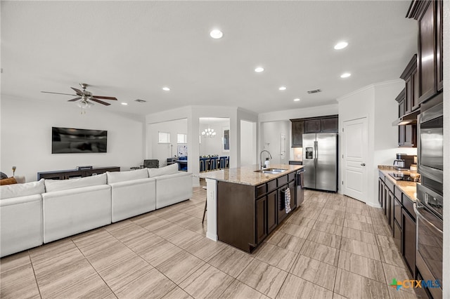 kitchen with ceiling fan with notable chandelier, dark brown cabinetry, sink, a kitchen island with sink, and appliances with stainless steel finishes