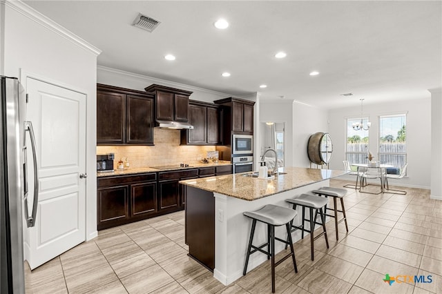 kitchen with a kitchen bar, a center island with sink, hanging light fixtures, sink, and appliances with stainless steel finishes