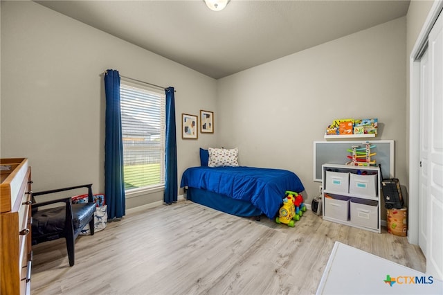 bedroom with light hardwood / wood-style floors and a closet